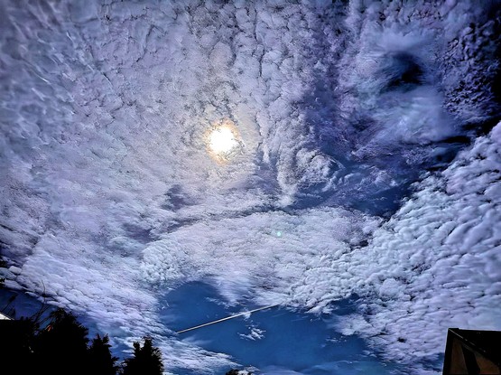 Foto des Nachthimmel mit dem unglaublich hellen Vollmond und wunderschöner  Zuckerwatte Bewölkung